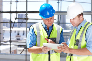 Two engineers working something out on their tablet while at a construction site